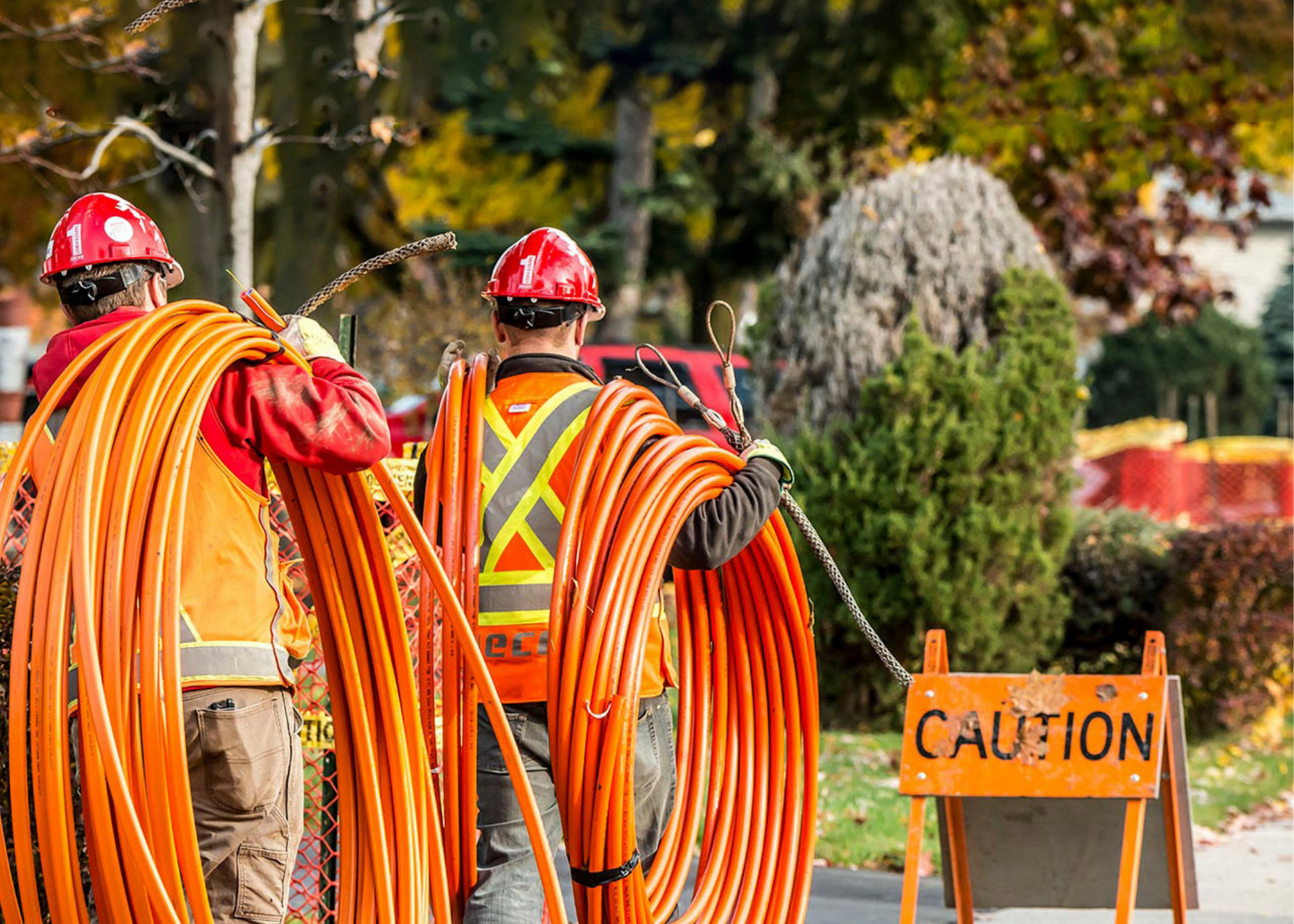 Construction workers walking with orange tubes